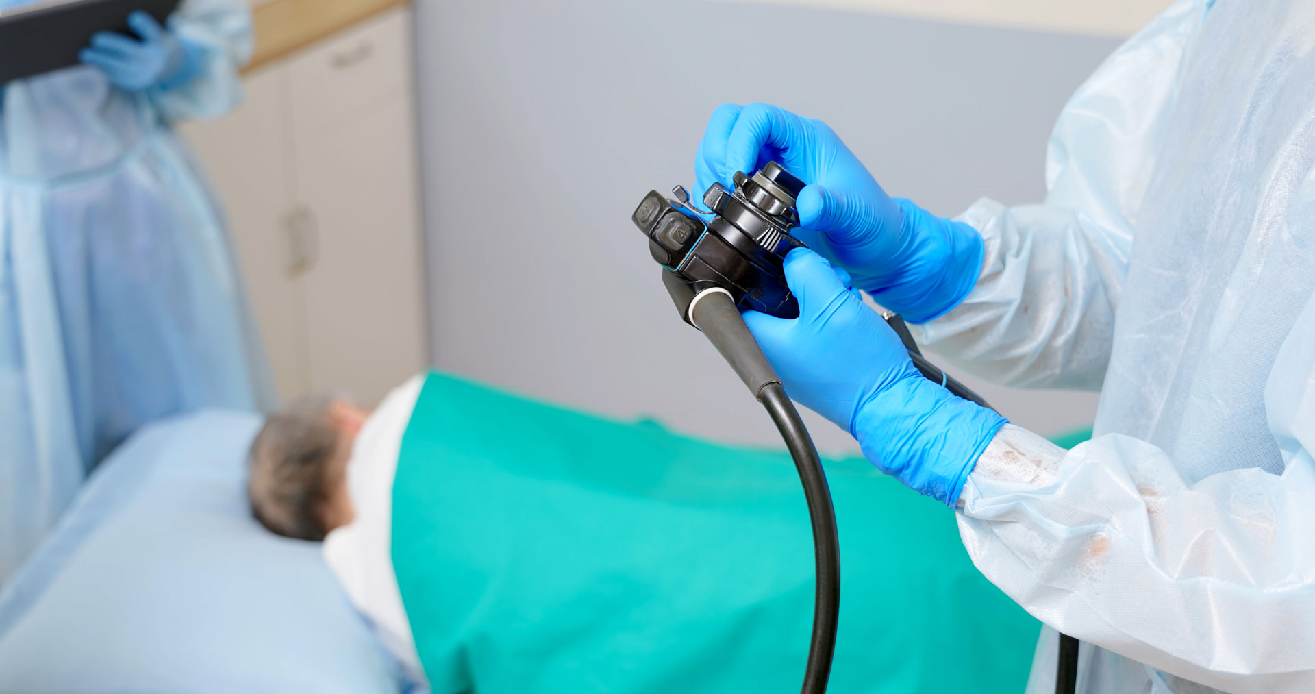Nahaufnahme eines Arztes in Schutzkittel, der bei einem älteren Mann im Krankenhaus eine Darmspiegelung durchführt.